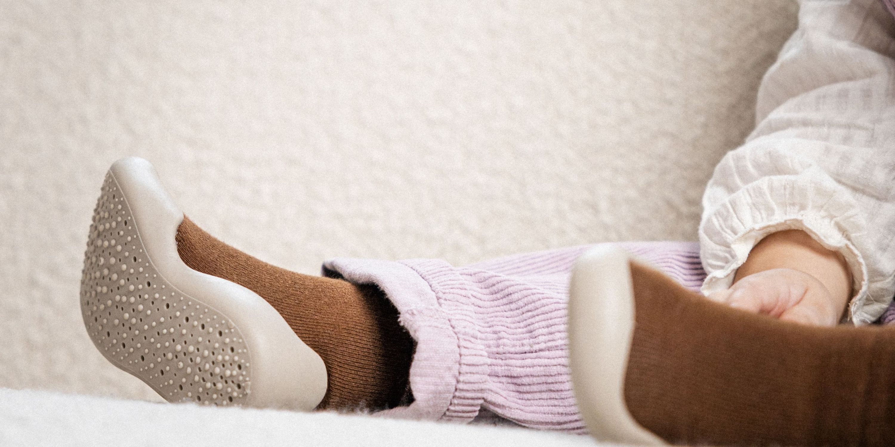 Barn iført brune begyndersko med skridsikker sål, liggende afslappet på en sofa