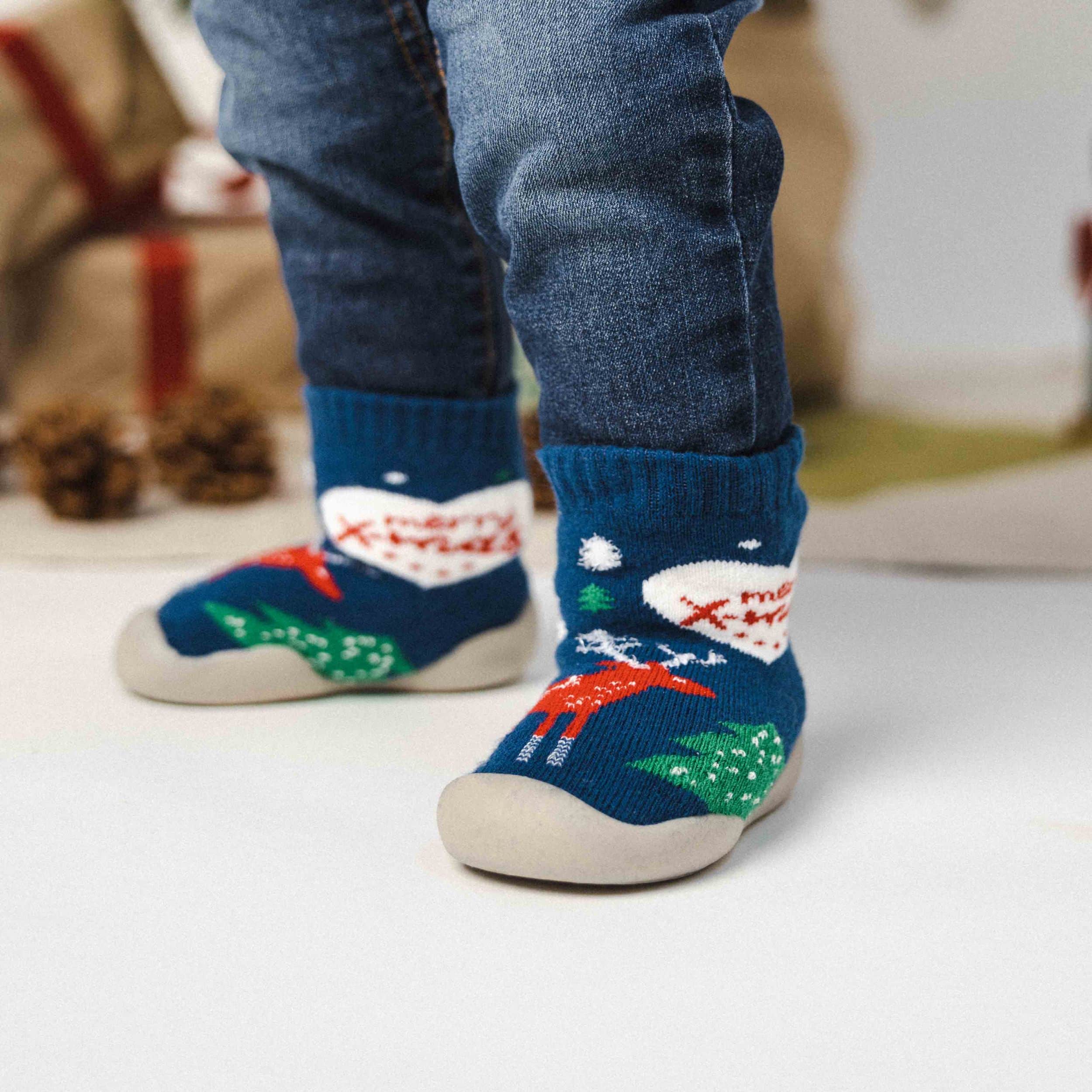 Barn iført blå julesko med rensdyrmotiv og skridsikker sål.